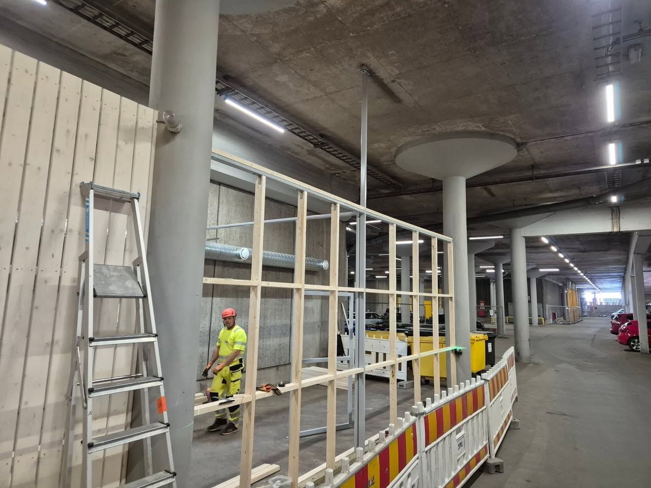 Asentaja kokoaa jätekatoksen runkoa pysäköintihallissa